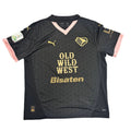 Gray sports jersey with 'Old Wild West Bisaten' text on a round white table.