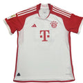 White sports jersey with red accents on a gray surface, featuring Adidas and Bayern Munich logos.